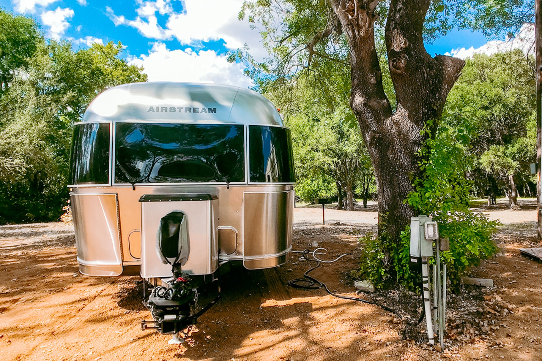 Airstream on full-hookup RV site under oaks